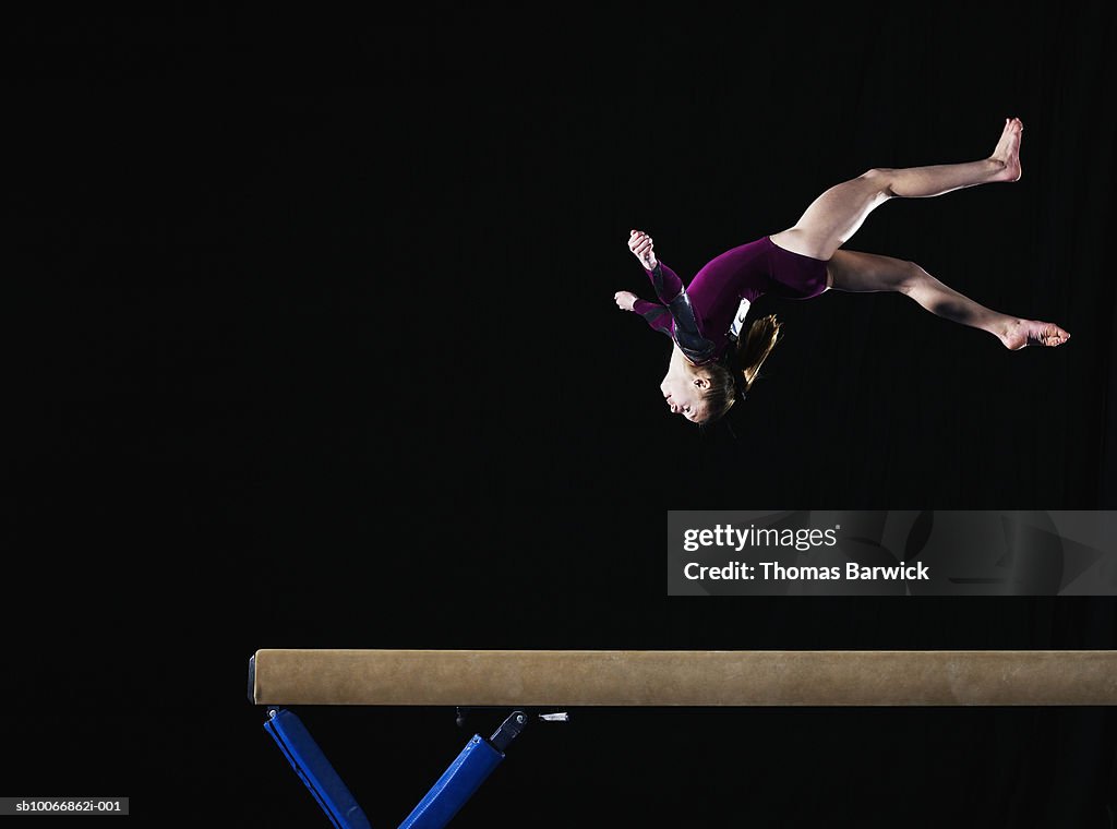 Gymnast (12-13) flipping on balance beam