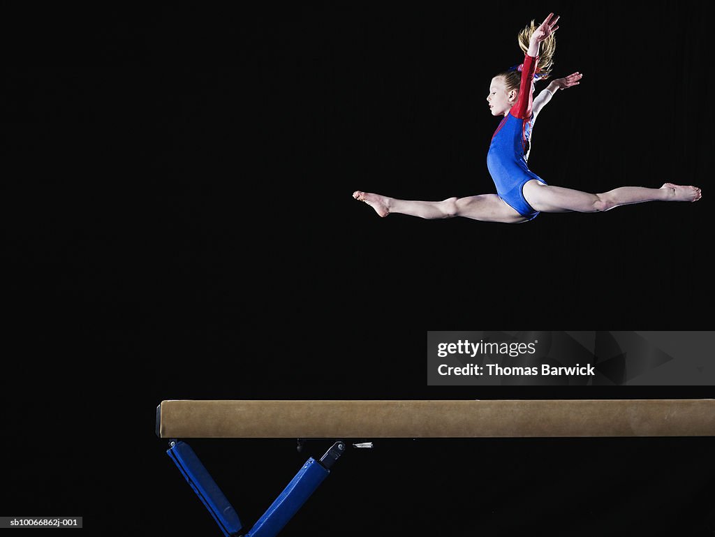 Gymnast (9-10) leaping on balance beam
