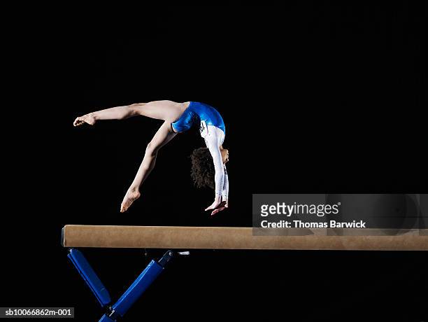 gymnast (9-10) flipping on balance beam, side view - gymnastiek stock-fotos und bilder