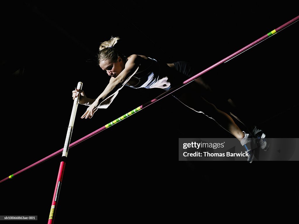 Female pole vaulter clearing bar