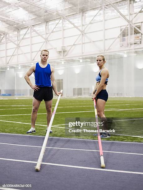 male and female pole vaulters on indoor track, portrait - stabhochsprung stock-fotos und bilder