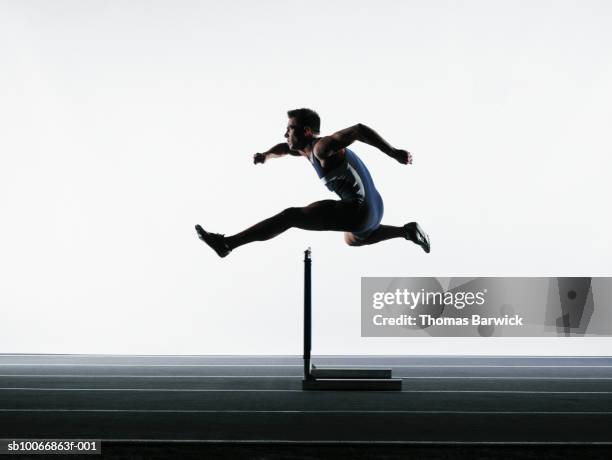 male runner jumping over hurdle - barrer stock pictures, royalty-free photos & images