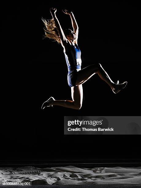 female athlete long jumping, mid air - アスリート　黒背景 ストックフォトと画像