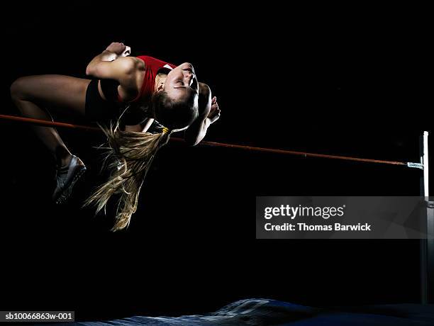 female high jumper in motion - hochsprung stock-fotos und bilder