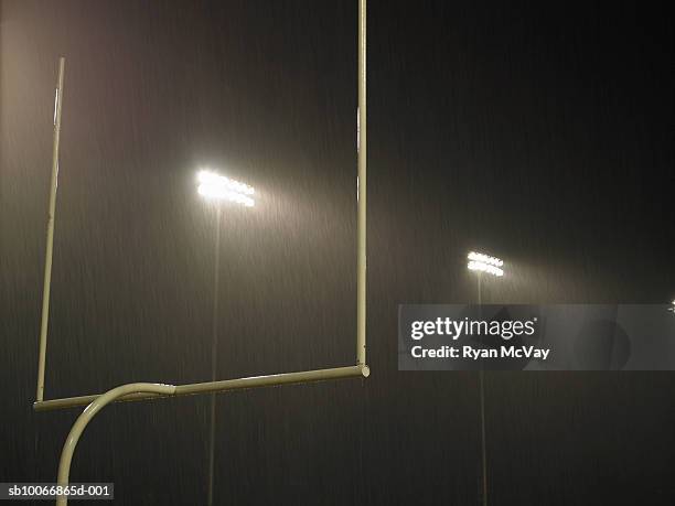 floodlight illuminated at night, goal in foreground - palo della porta foto e immagini stock