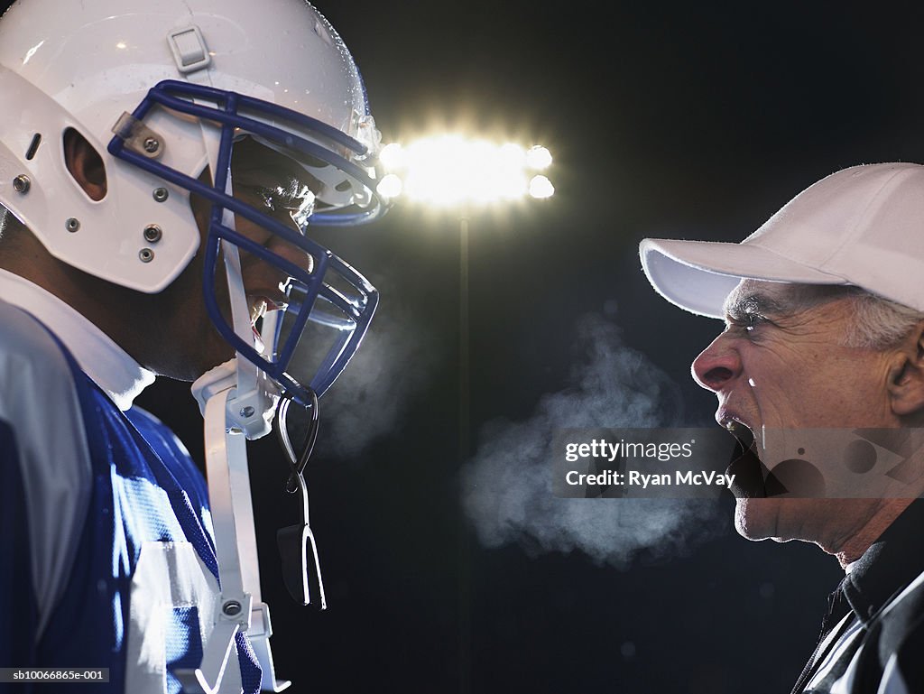 American football player and referee arguing, side view