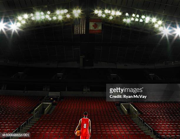 basketball player standing on court holding basketball, rear view - basketball stadium fotografías e imágenes de stock