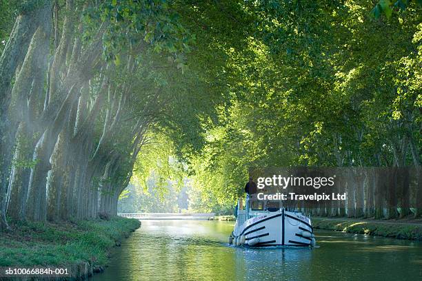 france, languedoc, carcassonne, boat in tree lined canal - occitanie stock pictures, royalty-free photos & images