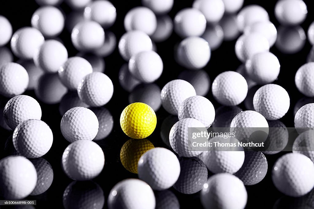 White golf balls with one yellow one
