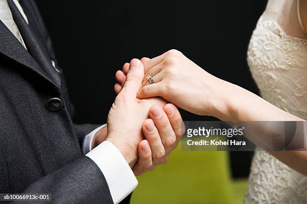 bride and groom with wedding rings, holding hands, mid section, side view - wedding vows foto e immagini stock
