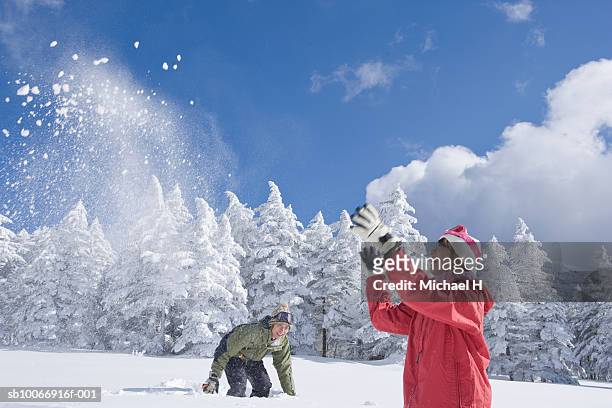 young couple throwing snow near forest - japan snow stockfoto's en -beelden