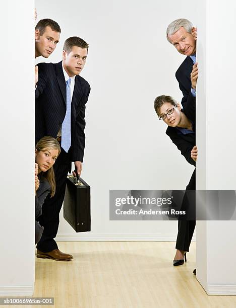 group of business people peeking around corner - peeking stock-fotos und bilder