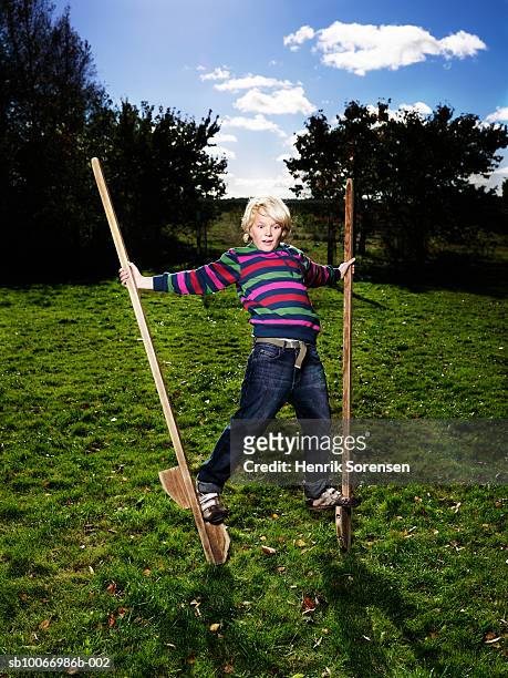 boy (10-11) balancing on stilts - échasses photos et images de collection