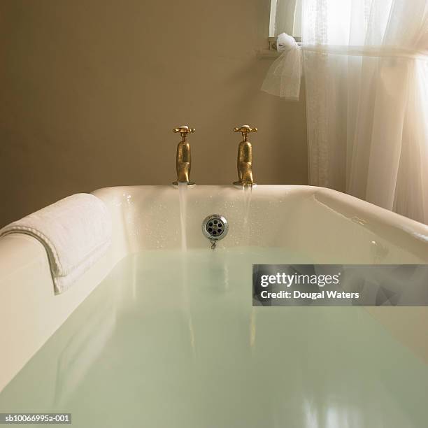 free standing bath with taps running - bathtub stock-fotos und bilder
