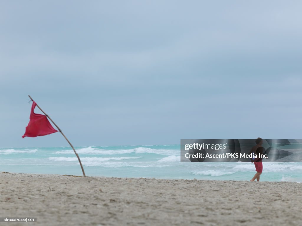 Man running at beach by warning flag