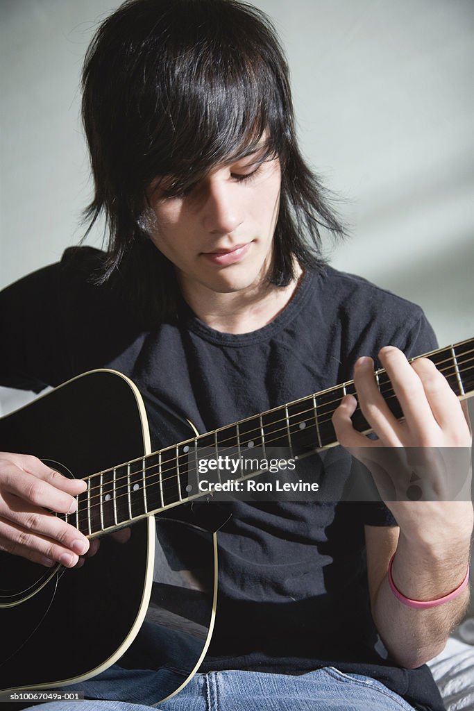 Teenage boy (14-15) playing guitar, close-up