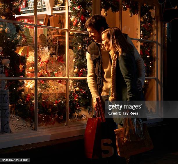 young couple looking at christmas display in shop, smiling - christmas shopping 個照片及圖片檔