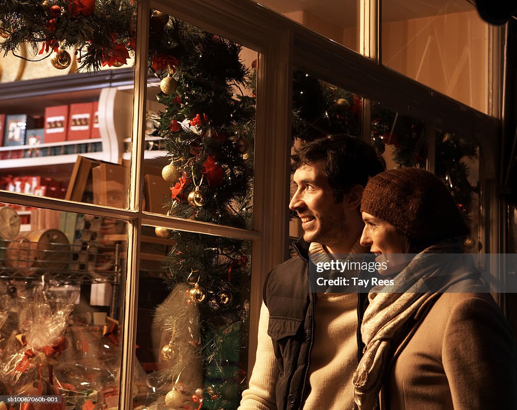 Couple looking at Christmas display in shop, smiling