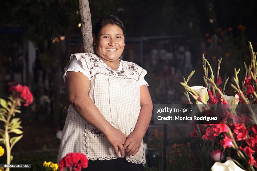 Mexico, Oaxaca, Mature woman making altar in cemetery, smiling, portrait