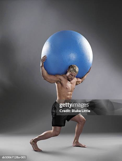 man holding exercise ball on back - titan stock-fotos und bilder