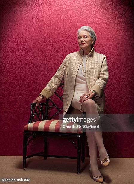 senior woman sitting on antique chair, portrait - bien vestido fotografías e imágenes de stock