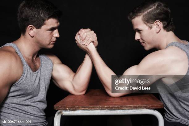 two young men arm wrestling, side view - echar un pulso fotografías e imágenes de stock