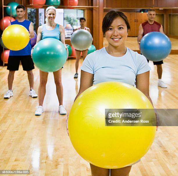 exercise class standing behind young female instructor, smiling - fitness ball stock pictures, royalty-free photos & images