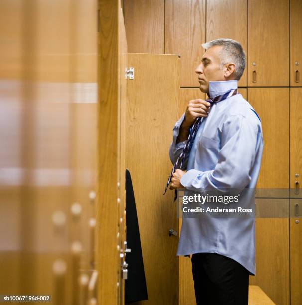 man getting dressed in locker room, side view - man in locker room stock pictures, royalty-free photos & images