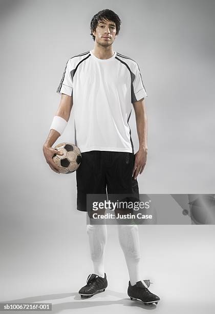 soccer player holding soccer ball, studio shot, portrait - fußballspieler stock-fotos und bilder