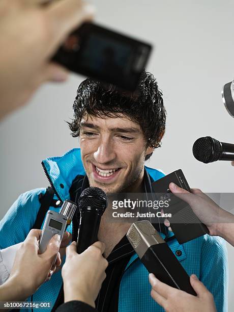 athlete being interviewed by journalists, studio shot - mann anhimmeln stock-fotos und bilder