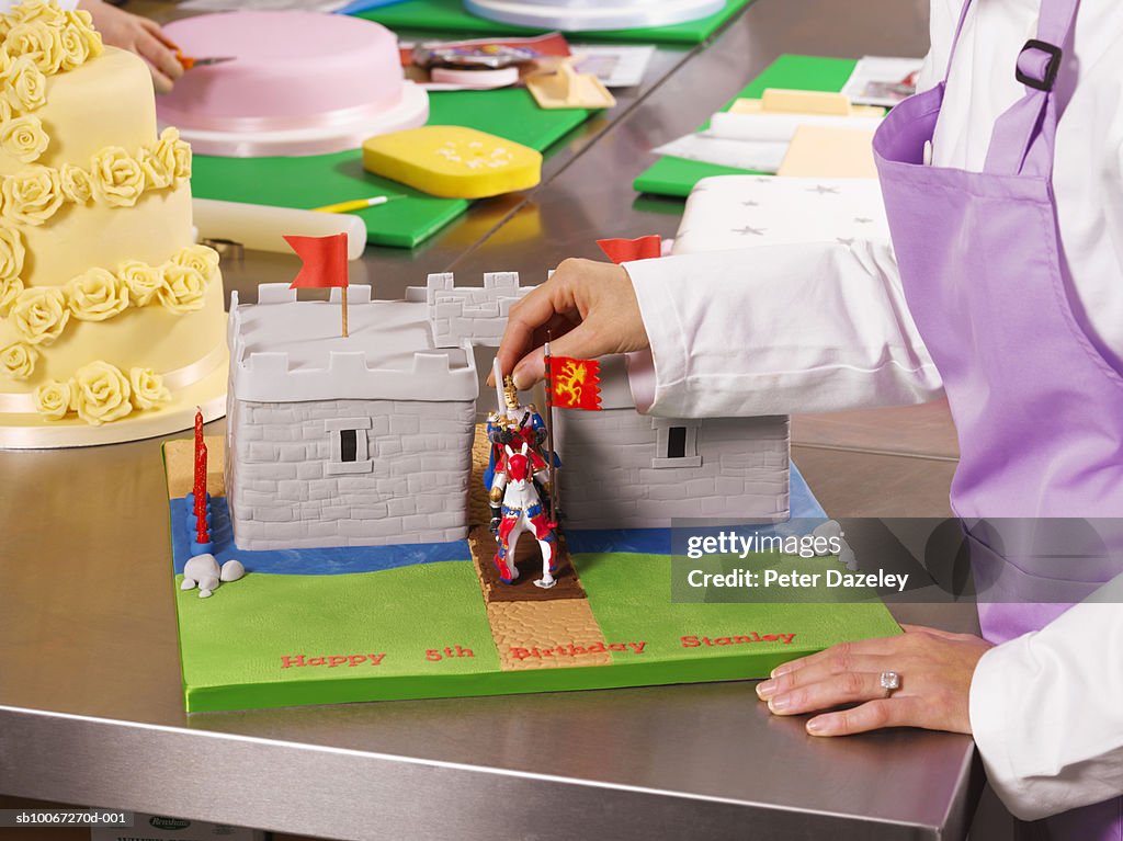 Mid adult woman decorating cake, mid section