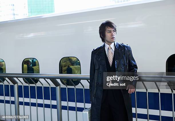 businessman standing at railway platform - オーバーコート ストックフォトと画像