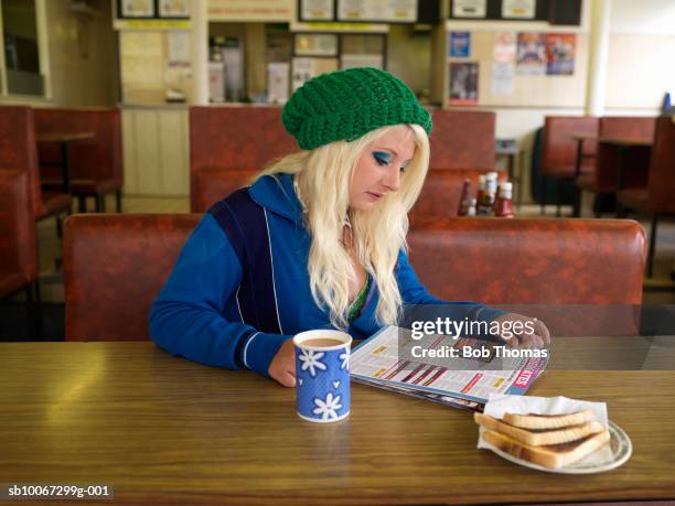 Young woman reading magazine in cafT