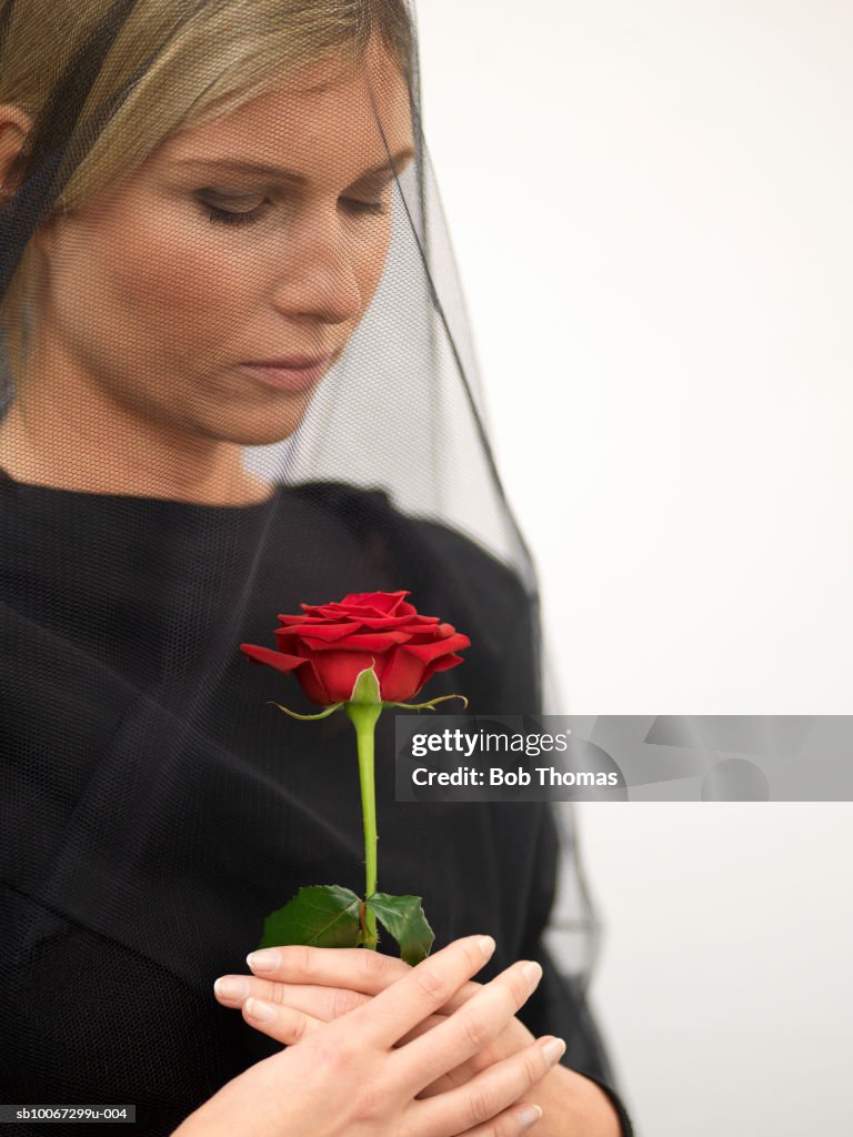 Woman wearing veil holding rose, close-up