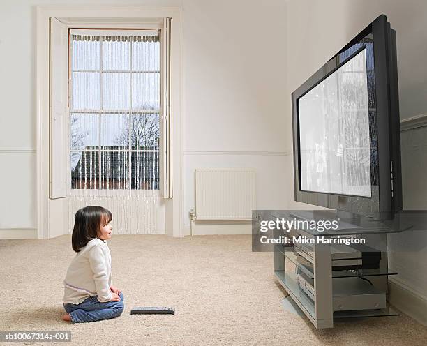 girl (2-3 years) sitting on carpet, watching tv, side view - big mike stock-fotos und bilder