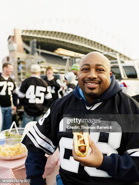 mature men eating hotdog at tailgate party, smiling - tailgate party stock pictures, royalty-free photos & images
