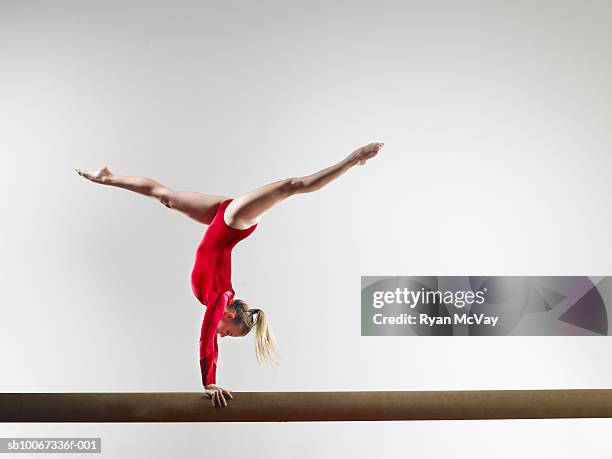 teenage gymnast (15-16) doing handstand on balance beam, studio shot - trave foto e immagini stock