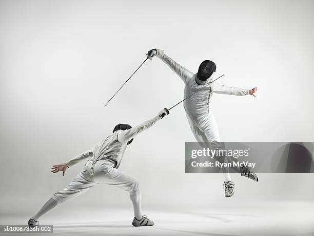 two men fencing, studio shot - fencing imagens e fotografias de stock