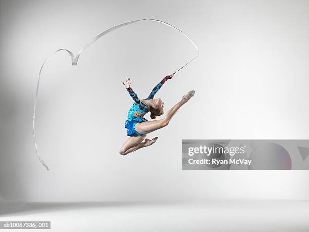 female gymnast (14-15) leaping with dance ribbon, studio shot - taking a shot - sport imagens e fotografias de stock