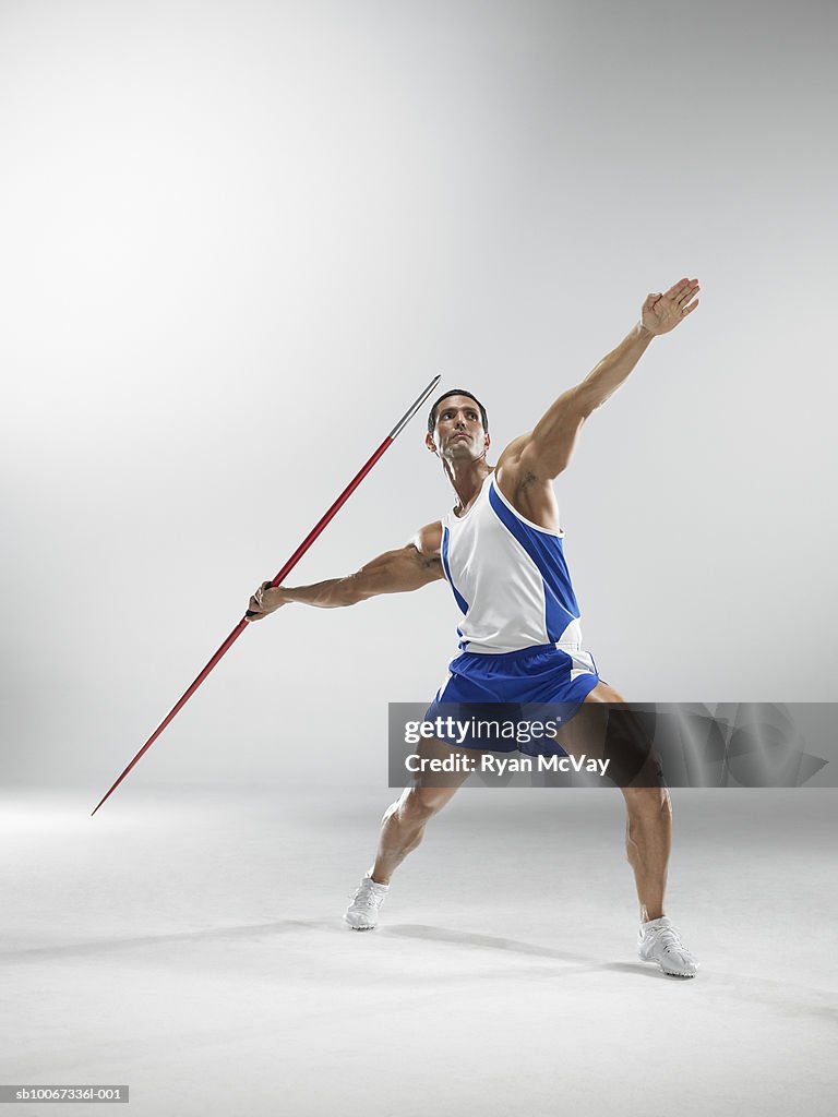 Man throwing javelin, studio shot