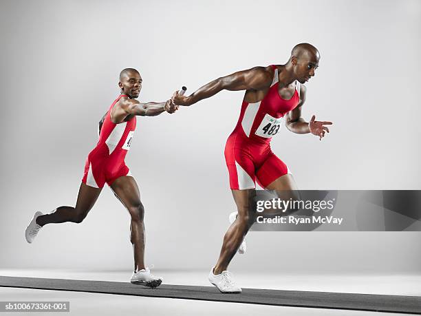 relayers passing baton (studio shot) - relay 個照片及圖片檔