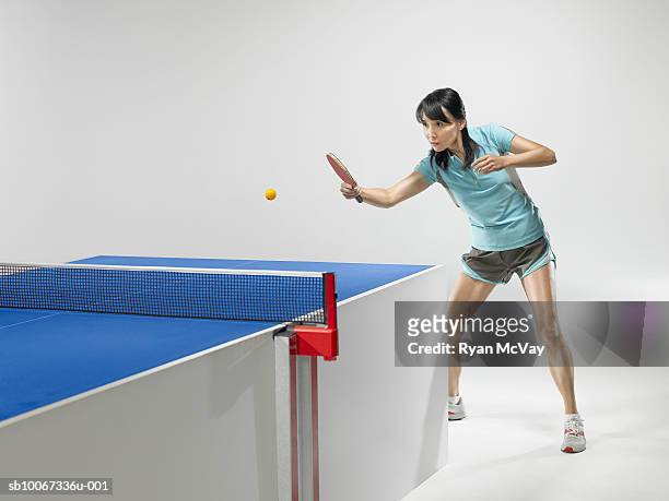 female table tennis player hitting ball  (studio shot) - women's table tennis stock-fotos und bilder