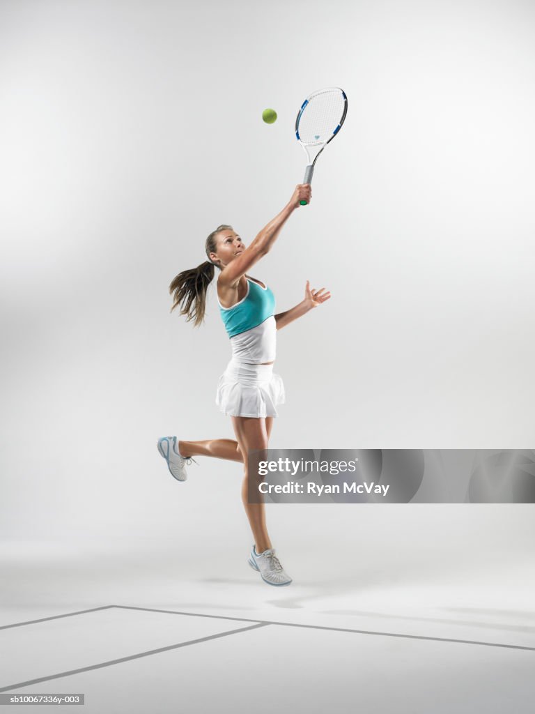 Tennis player making backhand hit (studio shot)