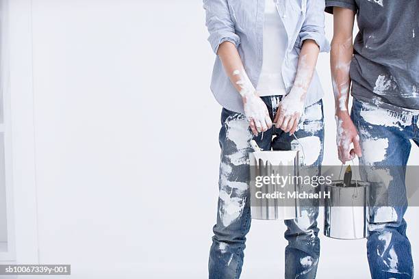 young couple wearing paint-spattered clothing, holding paint cans, mid section - messy boyfriend stock pictures, royalty-free photos & images