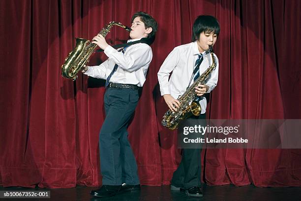 two boys (9-11) playing saxophones on stage - sax stockfoto's en -beelden