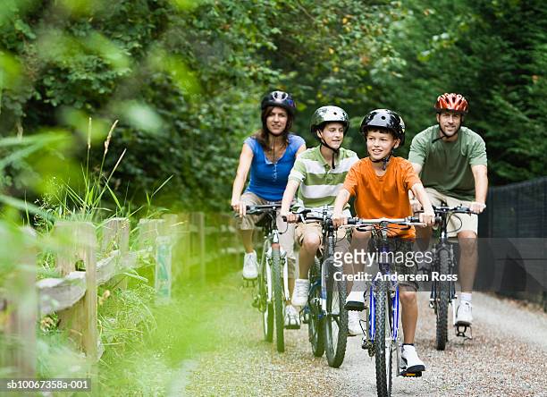 family cycling in park - ciclismo fotografías e imágenes de stock