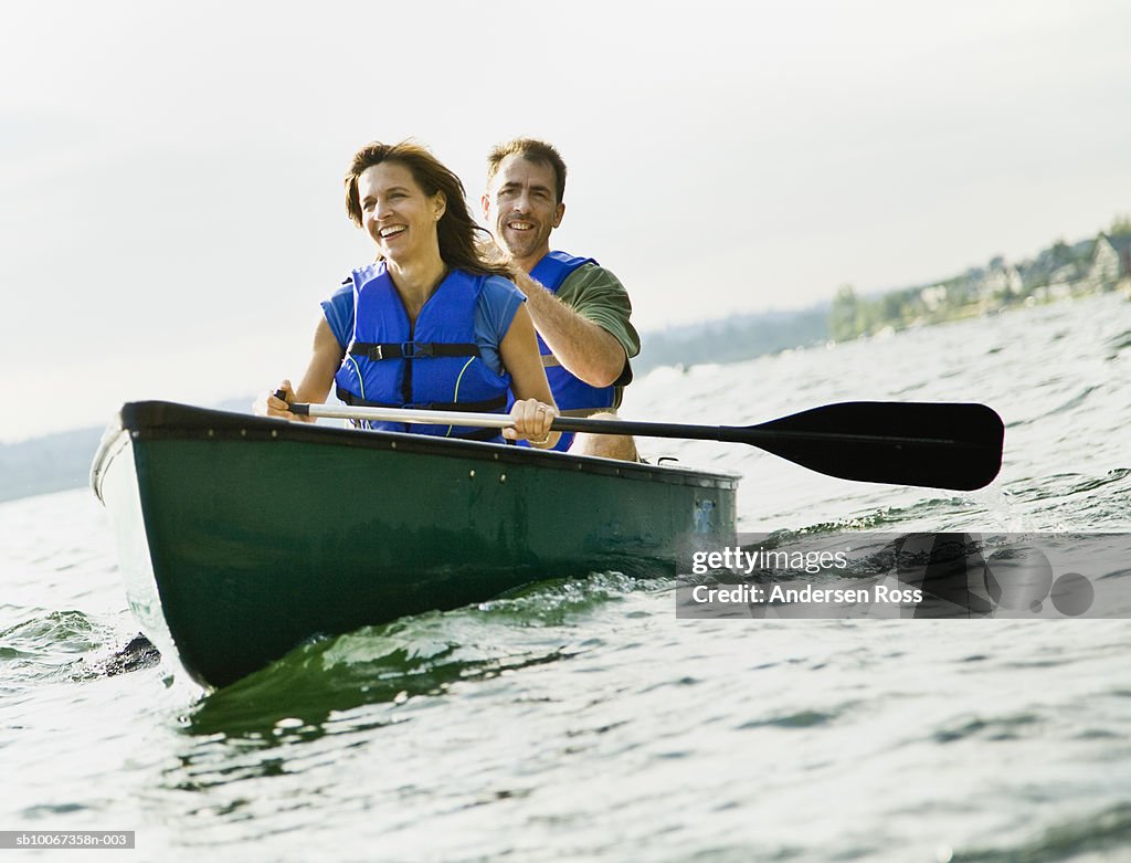 Mature couple canoeing in lake, smiling