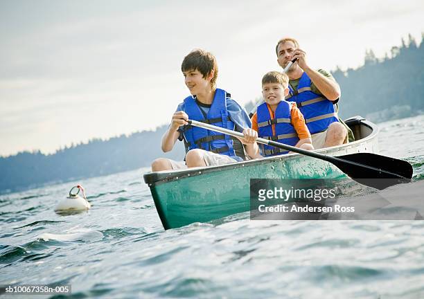 father and sons (10-15) canoeing in lake, smiling - 11 loch stock pictures, royalty-free photos & images