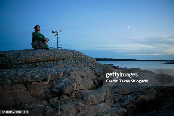 woman with telescope sitting on seashore at dusk - killbear provincial park stock pictures, royalty-free photos & images