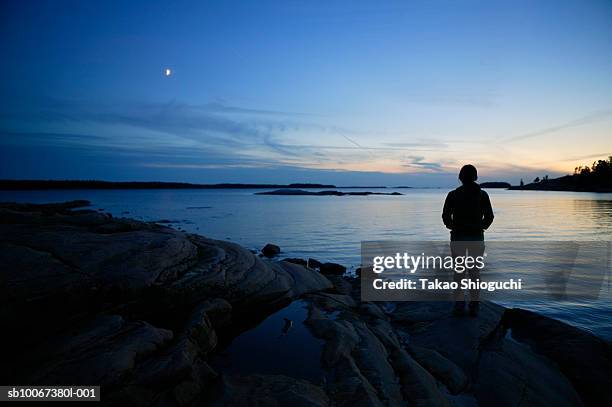 silhouette of woman standing on lakeshore at dusk - killbear provincial park stockfoto's en -beelden